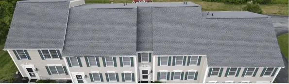 Aerial view of white townhouse complex with gray roofs and green shutters