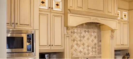 Elegant cream kitchen cabinets with decorative tile backsplash and built-in microwave