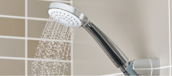 Chrome shower head spraying water with multiple spray settings in modern bathroom