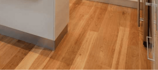 Modern kitchen with warm hardwood flooring and white cabinets with metal handles