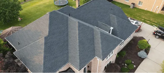 Aerial view of residential house with dark shingle roof and landscaped yard