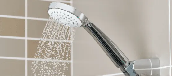 Chrome shower head spraying water with multiple spray settings in modern bathroom