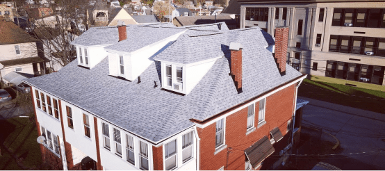 Aerial view of modern brick residential building with gray shingle roof
