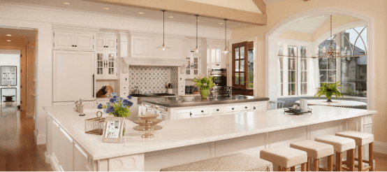 Modern white kitchen with large island, pendant lights, and arched window opening