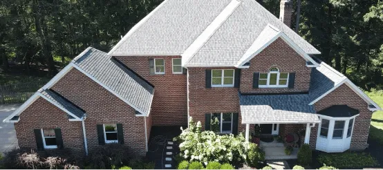 Aerial view of large brick house with attached garage surrounded by trees