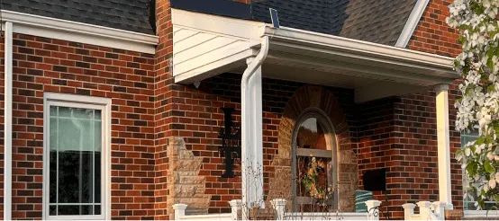 Red brick house exterior with covered front porch and decorative entrance door