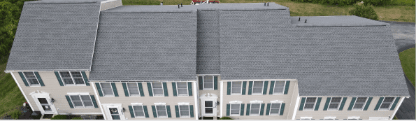 Aerial view of white townhouse complex with gray roofs and green shutters