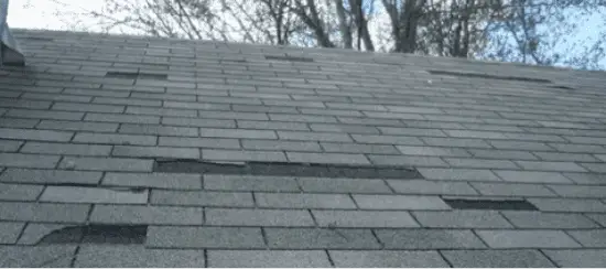 Damaged asphalt shingle roof with missing and loose shingles needing repair