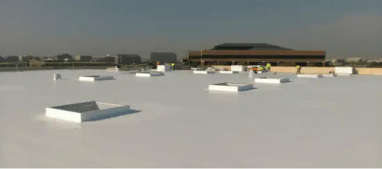 White commercial rooftop with HVAC units and industrial buildings in background
