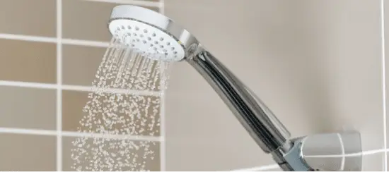 Chrome shower head spraying water with multiple spray settings in modern bathroom