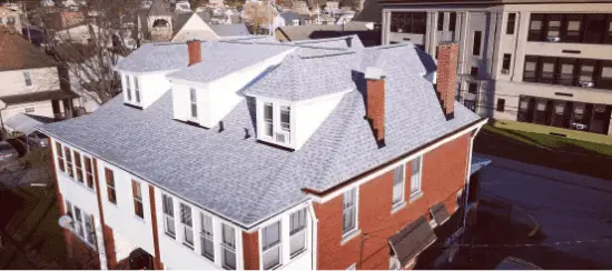 Aerial view of modern brick residential building with gray shingle roof