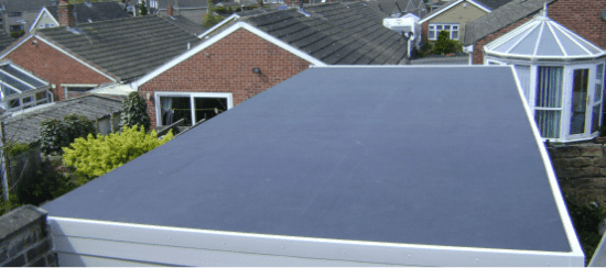 Grey flat roof on residential extension with white trim and brick houses