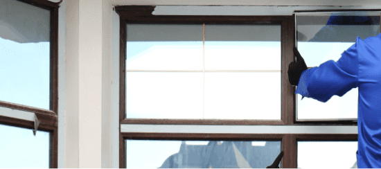 Professional window cleaner in blue uniform cleaning large commercial windows