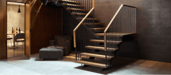 Modern floating wooden staircase with black metal railings in luxury home interior