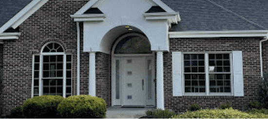 Elegant brick house front entrance with white columns and arched doorway