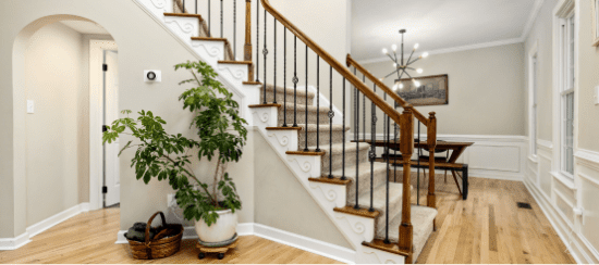 Modern home interior with wooden staircase, metal railings, and houseplant