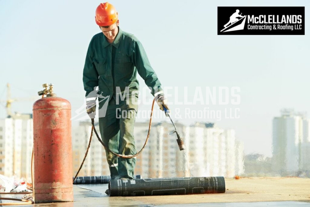 Professional Roofer In Safety Gear Using Torch To Install Waterproof Membrane On Roof