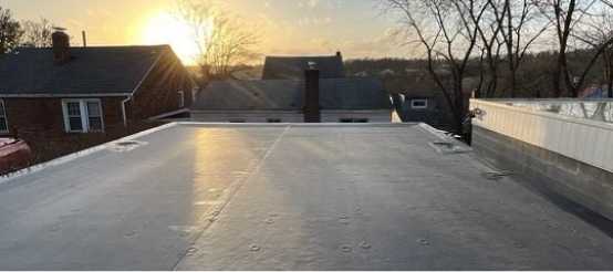 Flat roof construction site at sunset with residential houses in background