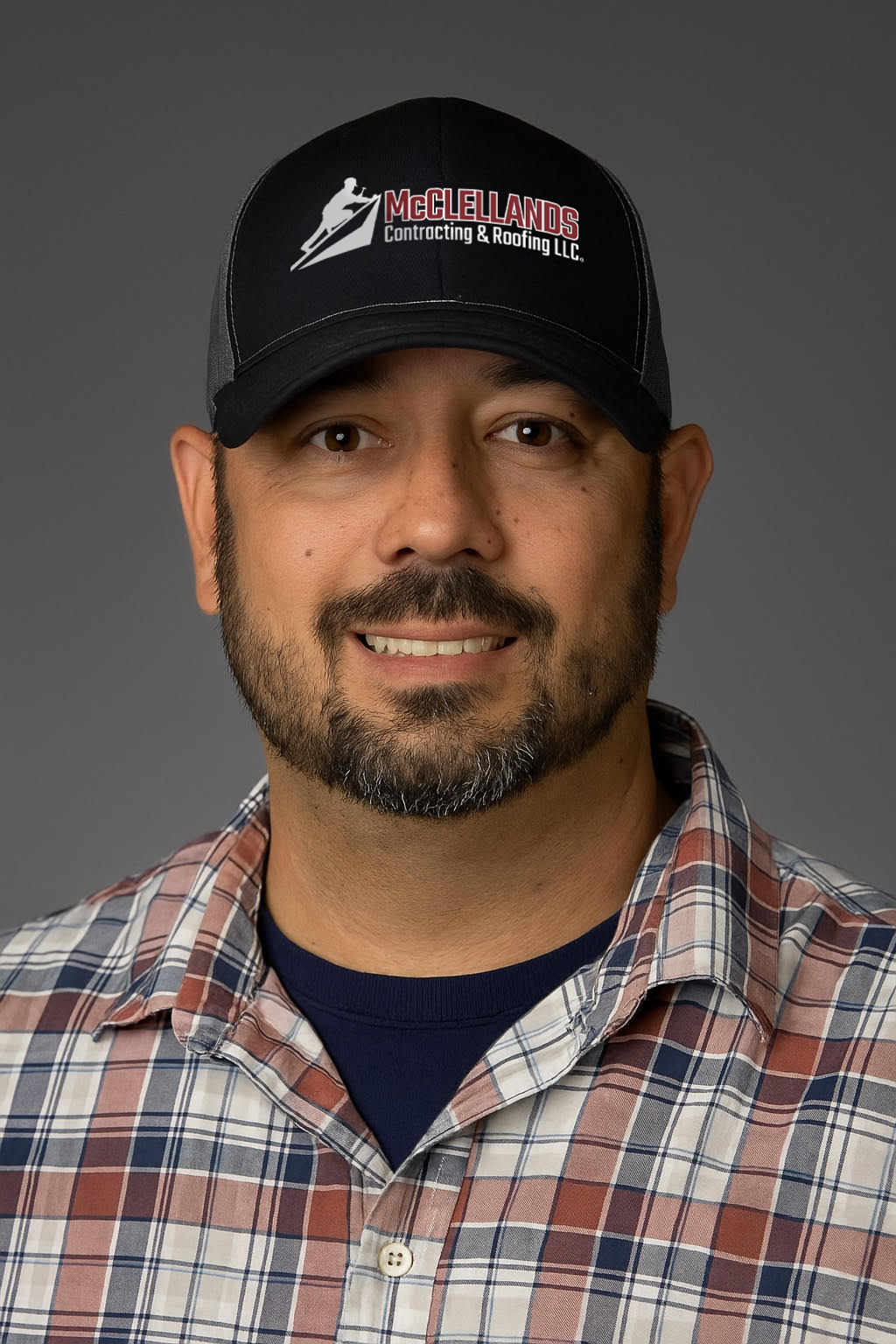 Professional headshot of smiling man wearing McClellands Contracting & Roofing cap