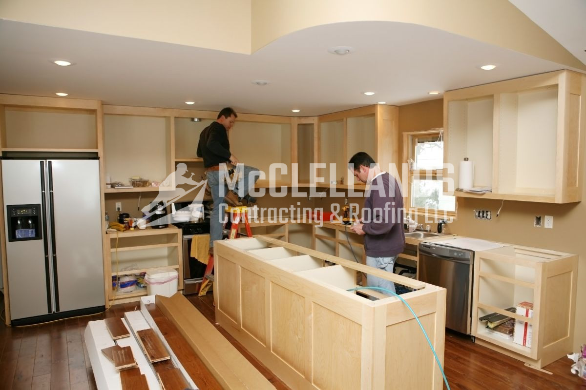 Kitchen remodeling underway with workers installing cabinets