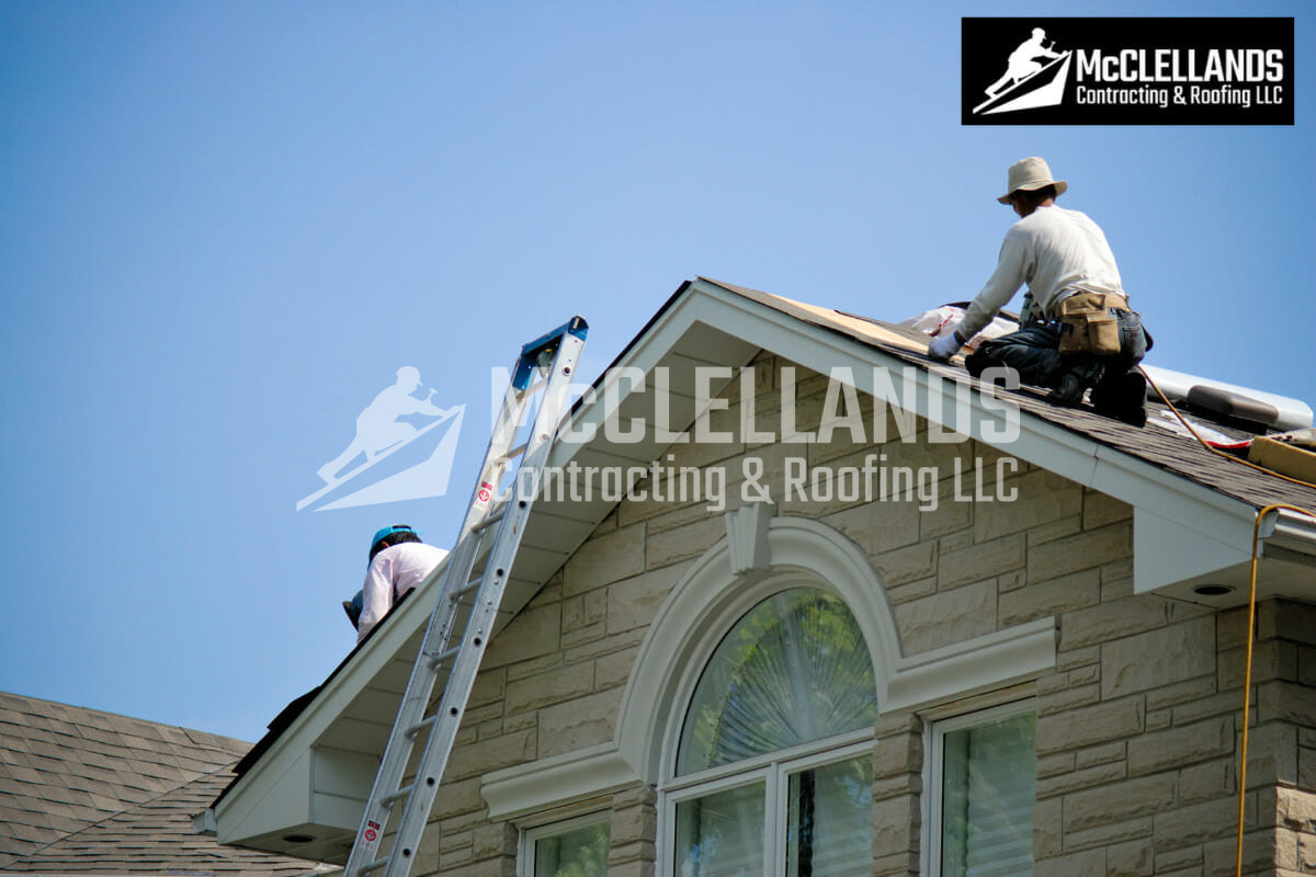 Roofers at work on a house roof under a clear blue sky