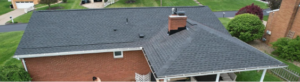 Aerial view of a suburban brick house with a dark shingle roof.