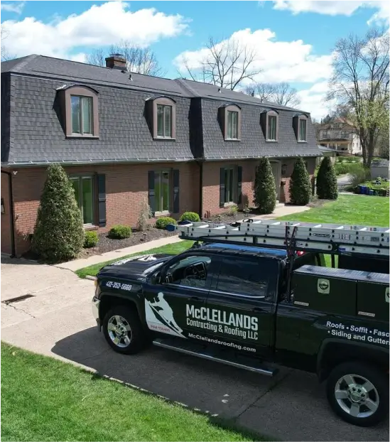 A large brick house with a dark roof, with McClellands contracting truck parked outside.