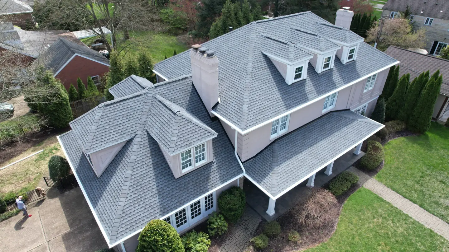 Aerial view of a two-story suburban house with new grey roofing tiles.