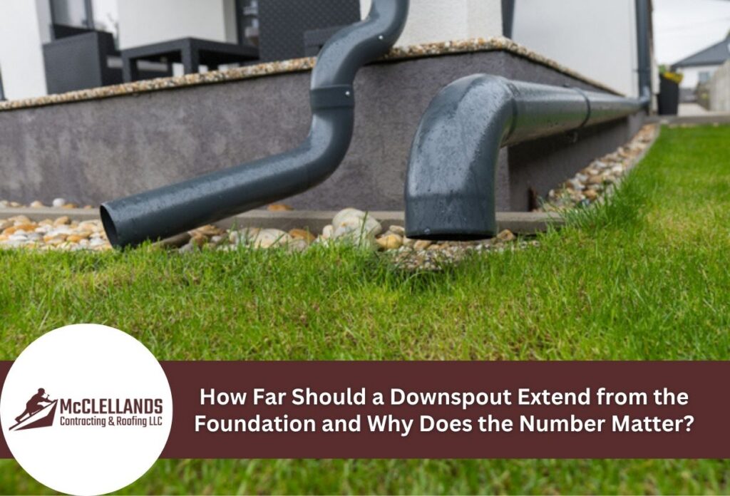 Black downspout extending from house foundation over green grass.