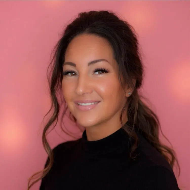 Smiling woman with dark hair against a pink background