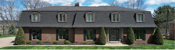Elegant brick house with dormer windows and manicured front yard.