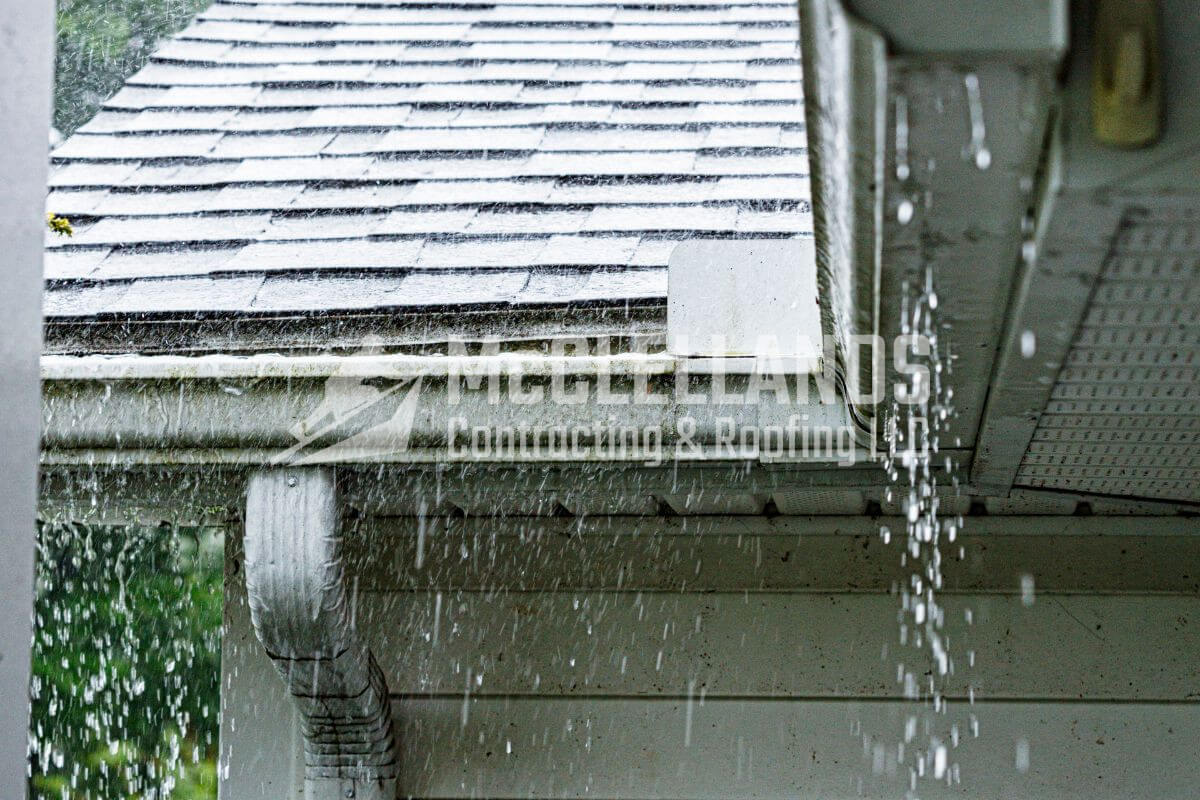 Rainwater cascading off a shingled roof and gutter