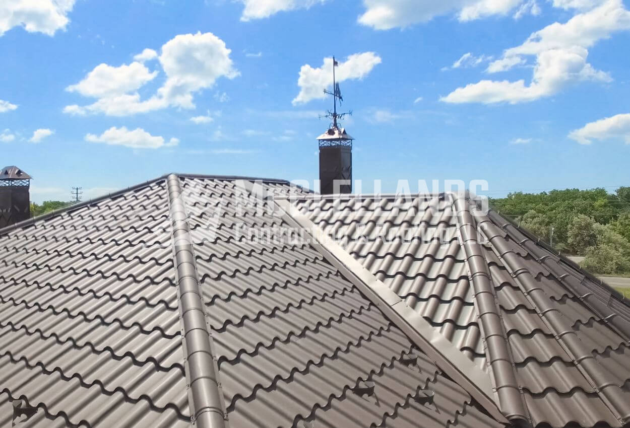 Metal roof with tile-like design under a bright blue sky.