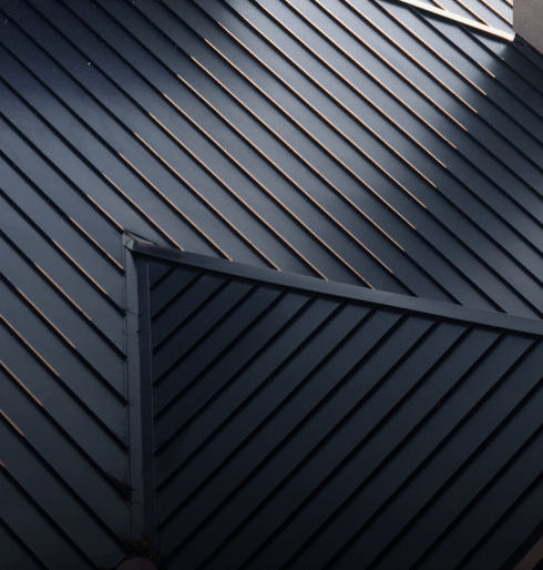 Close-up view of sleek modern metal roof design with sunlit lines.